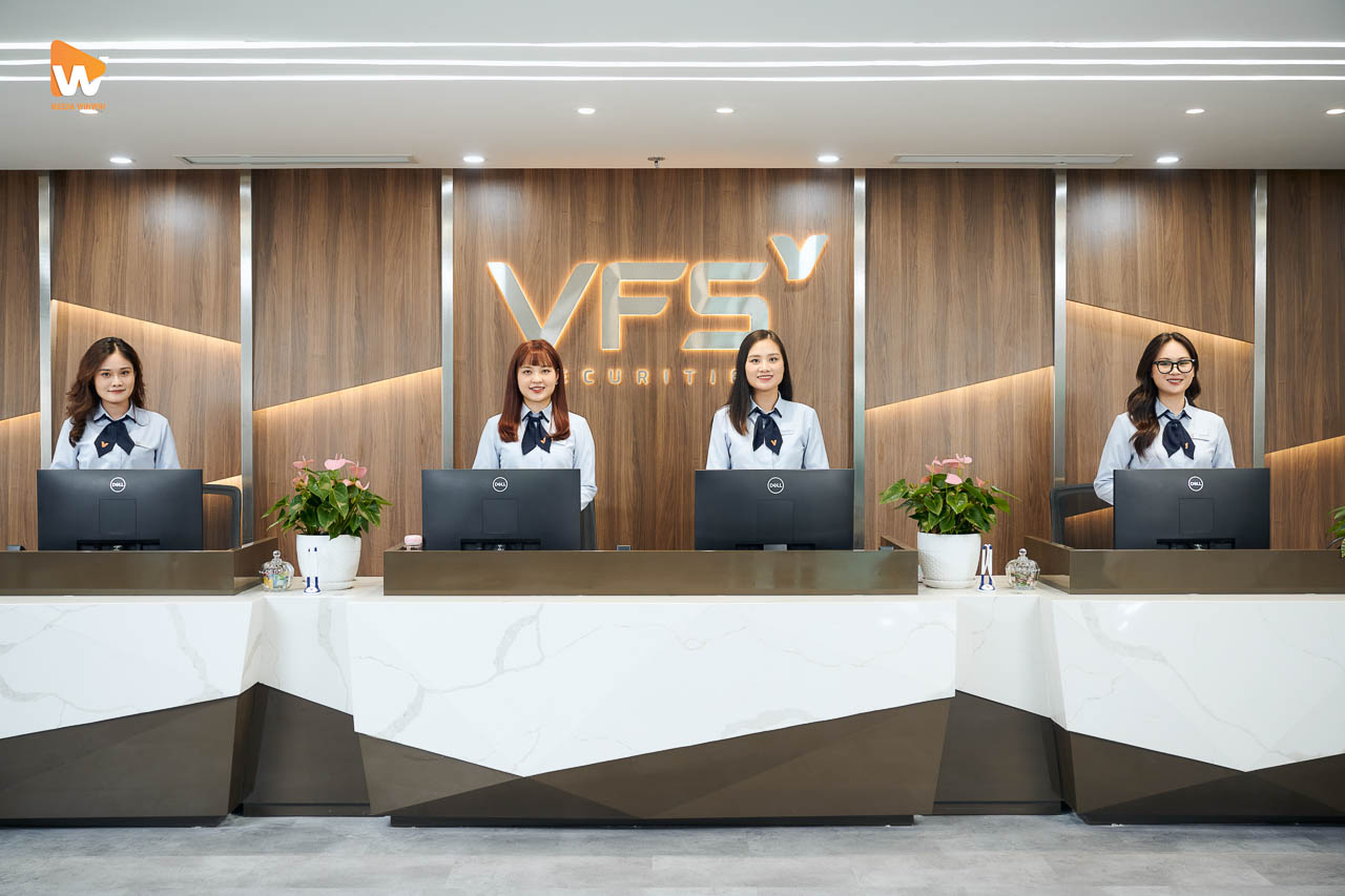 Quầy lễ tân VFS Securities với logo chữ nổi và nhân viên đón khách